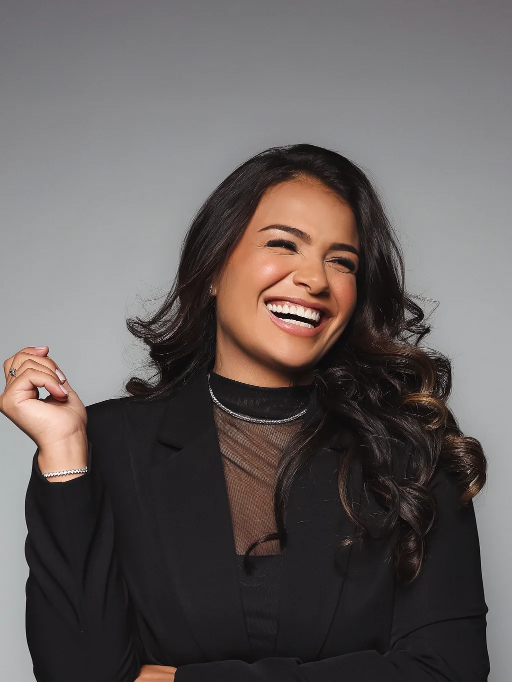 Dra. Thayná Souza sorrindo, de blazer preto
