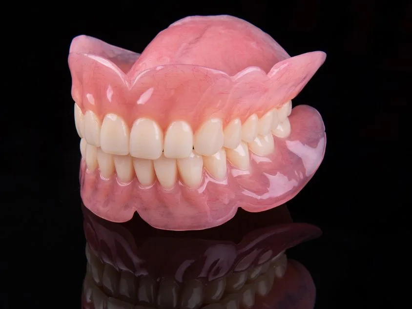 Foto ilustrativa de uma prótese dentária total sobre fundo preto